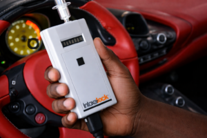 Hand holding Intoxalock in Ferrari interior